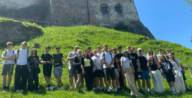 Grupa młodzieży z opiekunami z ruinami zamku w tle