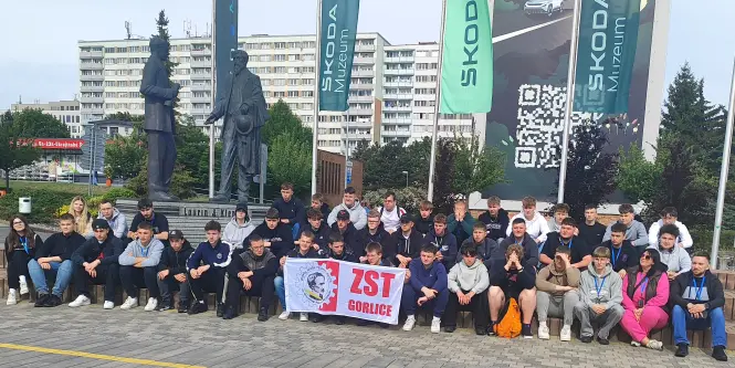 Grupa młodzieży z opiekunami przed flagami w Pradze